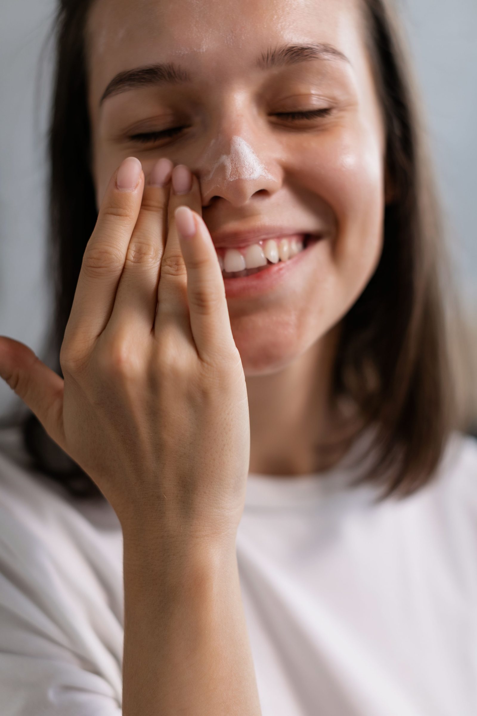 Woman applying skincare cream with a smile